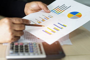 Asian accountant working and analyzing financial reports project accounting with chart graph and...