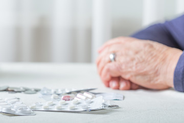 Closeup senior woman hands with pills and coins  on table at home. An elderly pensioner counts...