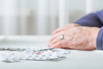 Closeup senior woman hands with pills and coins on table at home. An elderly pensioner counts money.