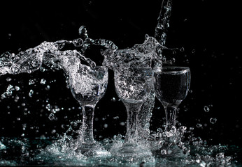 glasses with water with splashes on a black background