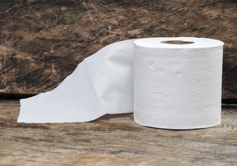 white tissue paper, roll of toilet paper on wood background 