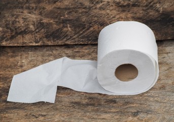 white tissue paper, roll of toilet paper on wood background 