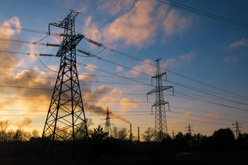 Fototapeta premium High-voltage power lines during fiery sunrise