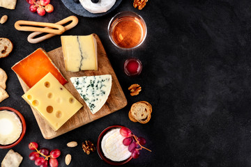 Cheese platter, shot from the top on a black background with copy space. Blue cheese, Brie, Dutch...