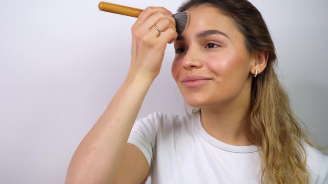 Beautiful mixed race young woman applying makeup. Confident and cute brunnete using makeup brush. Closeup portrait shot.