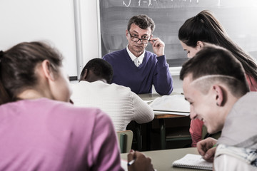 Obraz premium Professor watching as student write off on exams