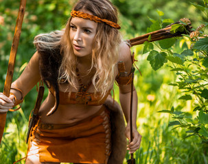 Beautiful girl archer with long blond hair with a bow and arrows dressed in leather