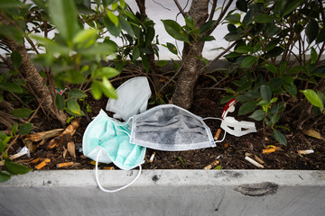People littering of garbage of used medical masks throw in the crevices of the bushes,hazardous waste,risk of disease,spread of germ,Coronavirus,Influenza virus,concept of throw trash in a trash can