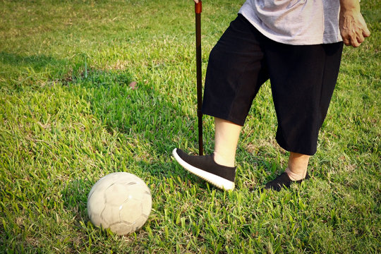 Healthy Asian Senior Woman Exercising With Old Soccer Ball,active Female Elderly With Walking Stick, Play Game The Football Outdoor On Grass,foot,legs Of Soccer Player Kicking The Ball,health Care