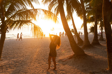 Beautiful girl at sunset on the beach having fun and enjoying life. Boracay Island in the Philippines. Against the background of cliffs, beach and sea. White beach