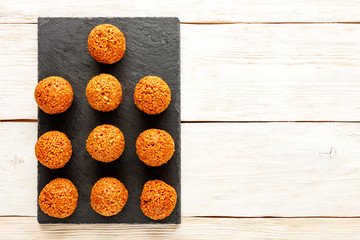 Homemade energy balls with walnuts, peanut, honey and banana lie on a gray cutting board slate, located on a light wooden table background, top view.
