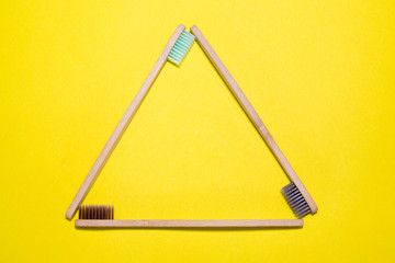 Recycling symbol made of bamboo toothbrashes on yellow background