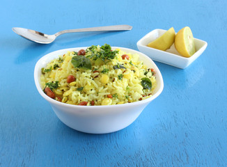 Lemon rice, a traditional, popular, delicious and south Indian vegetarian dish, in a bowl, and sliced lemons.