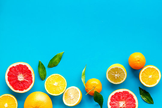Citrus fruits frame - halfs of lemons, grapefruits, leaves - on blue background top-down copy space