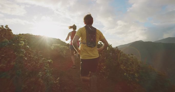 Two friends running into the sunset together on an epic mountain top, young adventurous ultra runners exploring the outdoors