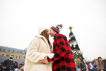 young beautiful couple boy in a red shirt and red hat girl in a white coat and white hat hold each other's hands