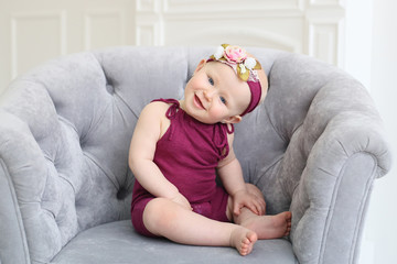 horizontal photo of baby sitting in a chair on a light background