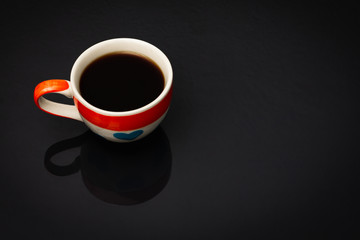 Heart pattern coffee cup In the cup there is black coffee on black background