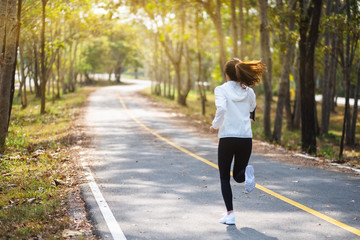 Rear view image of a young asian woman jogging in city park in the morning