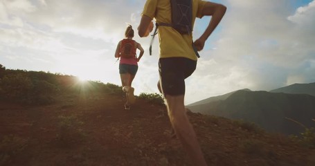 Two active friends running together on a mountain top into the sunset, young adventurous couple ultra running together, health and fitness outdoors concept - Powered by Adobe