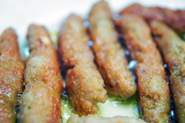 The long cutlet is fried in a red pan. She cooks the cutlet in a white pan . Juicy homemade cutlets beef, pork, chicken .
