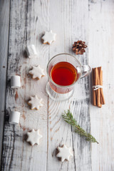 Christmas hot drink - mulled wine, cinnamon stick, star anise and festive Christmas gingerbread cookies over rustic wooden background with copy space, top view