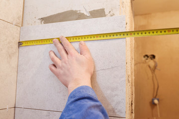 Worker makes repairs in the apartment. Measure tape and pencil in the hands of a builder. Dismantling the room. Closeup.