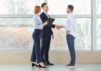 Bank manager and clients shaking hands in office