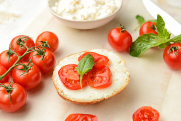 Slice of tasty bread with cream cheese and tomatoes on table
