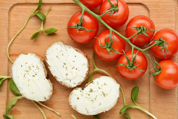 Slices of tasty bread with cream cheese and tomatoes on board