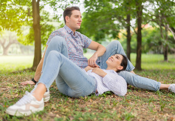 Fototapeta premium Couple young lover lying down on green grass in park together,Romantic and enjoying in moment of happiness time,Happy and smiling,Positive thinking,Eyes contact