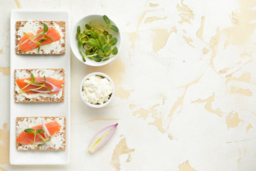 Sandwiches with tasty cream cheese and salmon on white background