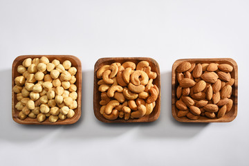 Hazelnuts, almonds and cashews in the wooden bowls on white background