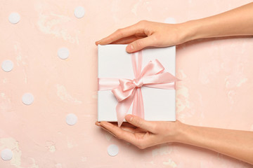 Female hands with beautiful gift box on color background