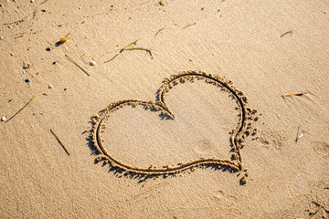 Fototapeta na wymiar Heart drawn in the sand on the beach. Love and travel concept. Empty space for text input