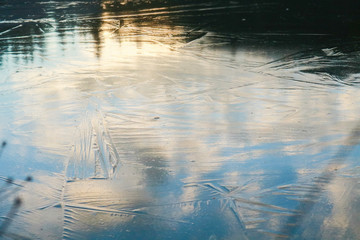 Lastra di ghiaccio che ricopre il laghetto e riflette i colori del cielo al tramonto, paesaggi e natura in inverno