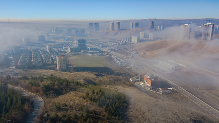 Landscape over the clouds in foggy weather. Hills of buildings in foggy weather. The drone and the...