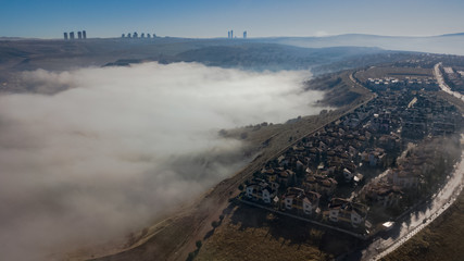 Landscape over the clouds in foggy weather. Hills of buildings in foggy weather. The drone and the...