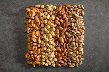 Group of nuts, hazelnuts, almonds, pistachios, cashews on the gray stone texture
