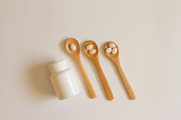 Assorted pharmaceutical medicine. Dosage. Tablets and capsules on a wooden spoon on a white background. Concept of medicine. Alternative homeopathy. Flatley. copyright of the text.