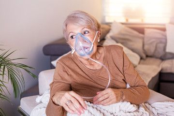 Sick elderly woman making inhalation, medicine is the best medicine. Ill senior woman wearing an...