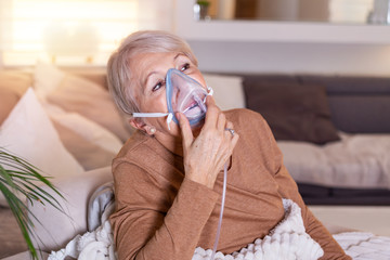 Sick elderly woman making inhalation, medicine is the best medicine. Ill senior woman wearing an...