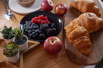 Succulents, croissants, berries, red apples on a wooden table
