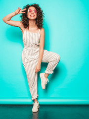 Portrait of beautiful smiling model with afro curls hairstyle dressed in summer hipster clothes.Sexy carefree girl posing near blue wall.Trendy funny and positive woman