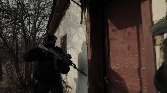 Special forces soldiers with weapons storm house