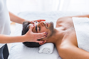 Man receiving facial massage at luxury spa. Young man relaxed in spa. Closeup of a man having head...