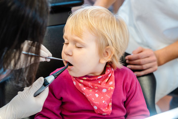 Woman dentist looking after baby teeth of a little girl