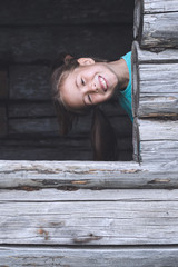Children peep out the window of an old wooden house and smiling. Summer vacation in the country