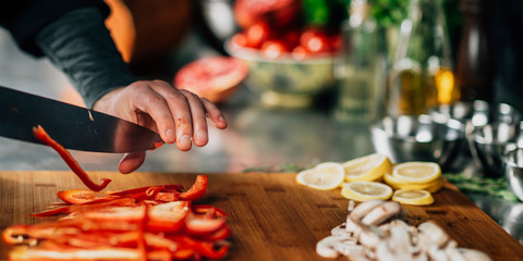 Cooking dinner - Chef Holding a Knife and Cutting Red Bell Pepper