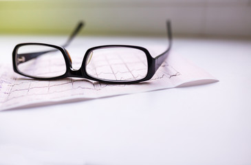 Cardiogram chart with glasses on table closeup. Space for text